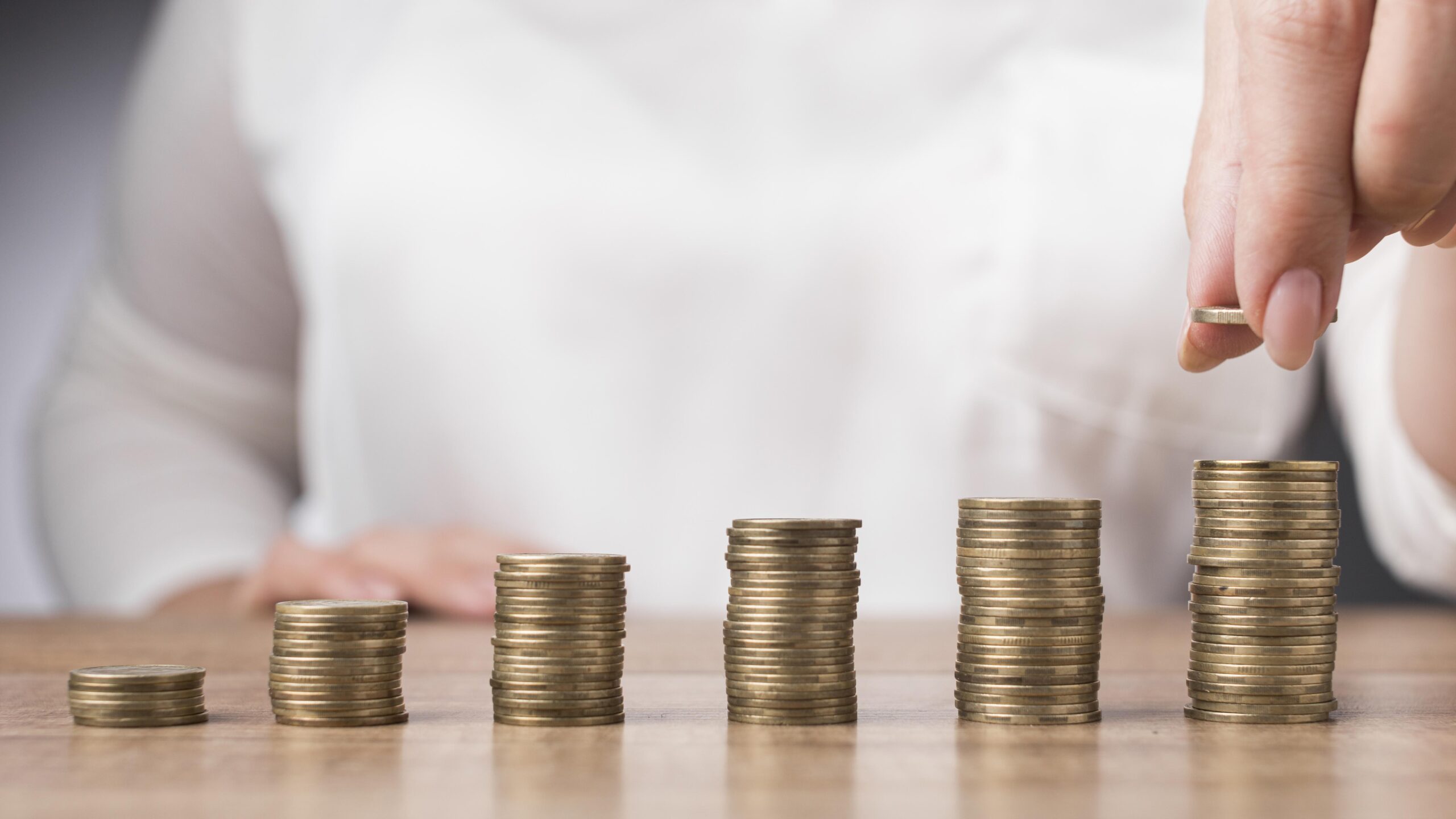 Woman placing coin on pile of coins.