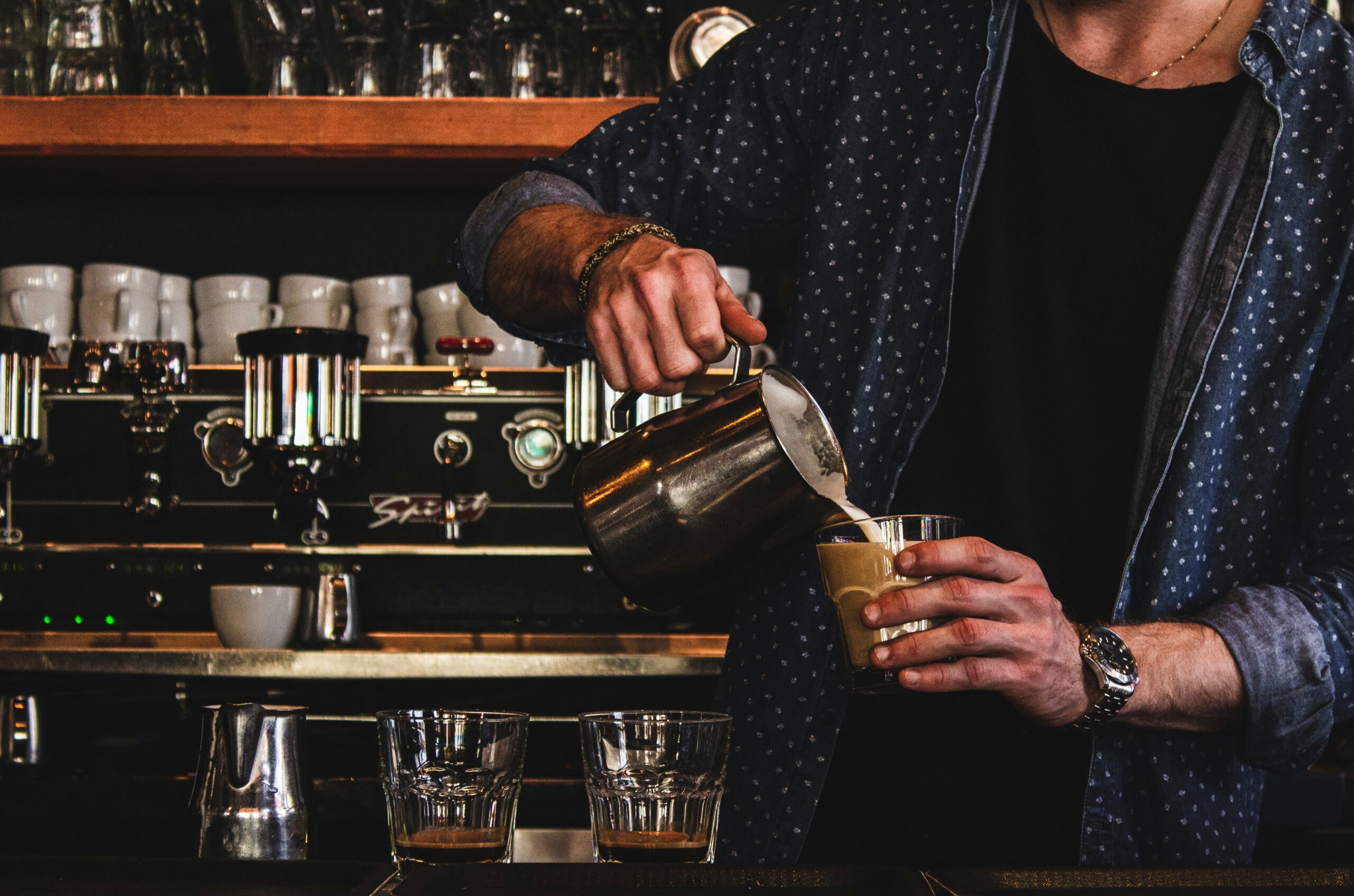 Barista pouring a coffee into a glass.