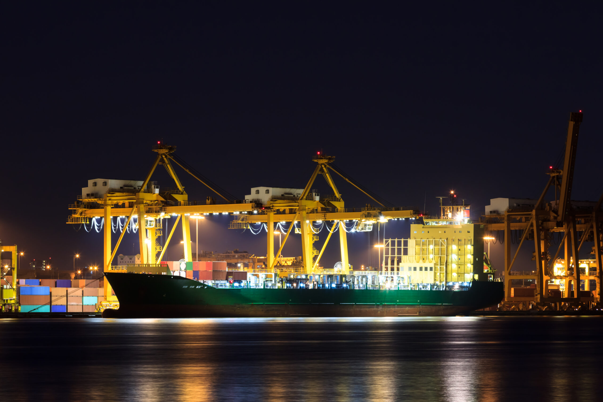 Container cargo freight ship at port at night.