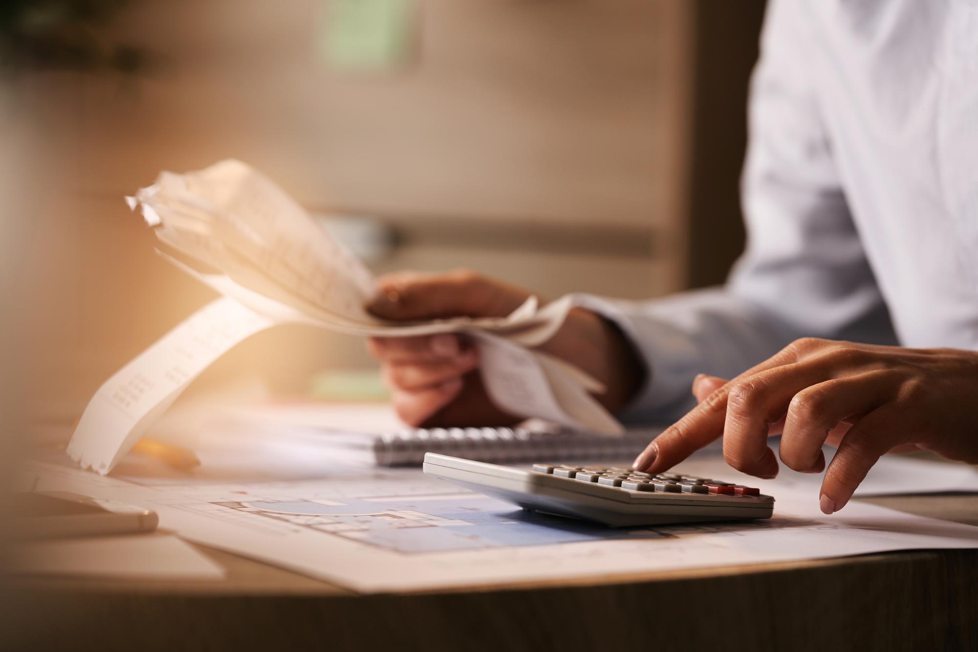 Closeup economist using calculator while going through bills taxes office.